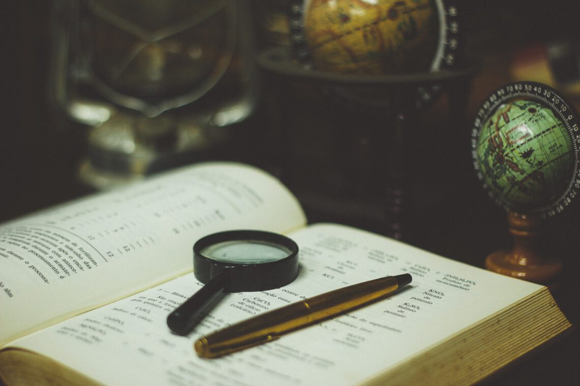 Schreibtisch mit Buch, Stift, Lupe und Globus