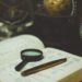 Schreibtisch mit Buch, Stift, Lupe und Globus