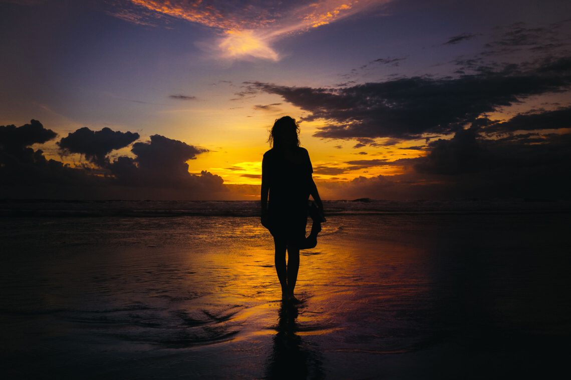 Frau am Meer zum Sonnenuntergang